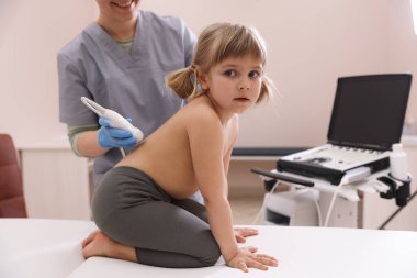 Küçük kızın böbrek ultrasonu muayenesini klinikte yapan sonograf.