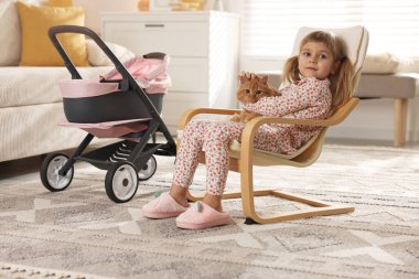 Evdeki koltukta oturan kızıl kedisi olan tatlı küçük kız.