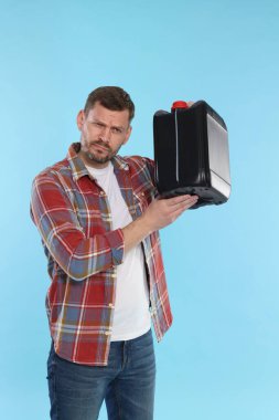 Açık mavi arka planda plastik kutu tutan adam.