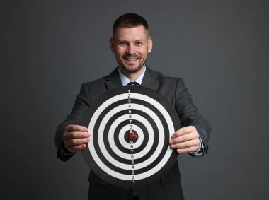 Hedef alınıyor. Dart tahtası ve gri arka planda oku olan bir adam.