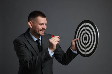 Hedef alınıyor. Dart tahtası ve gri arka planda oku olan bir adam.