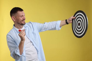 Hedef alınıyor. Sarı arka planda ok ve dart tahtası olan adam.