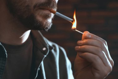 Arka planda kibrit yakan adam, yakın plan.