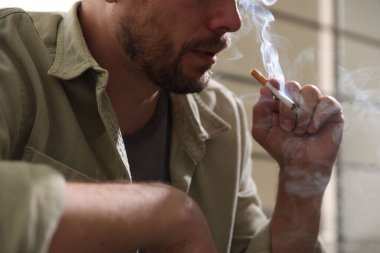 Arka planda sigara içen adam, yakın plan.