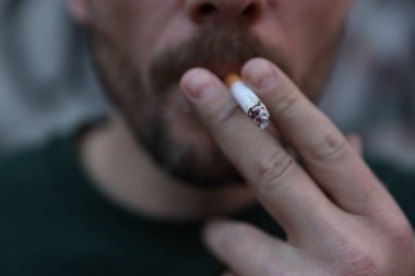 Arka planda sigara içen adam, yakın plan.