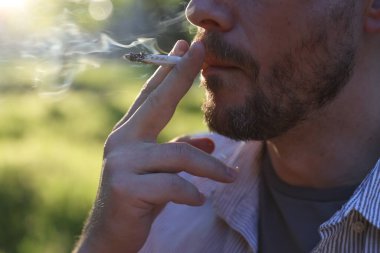 Arka planda sigara içen adam, yakın plan.