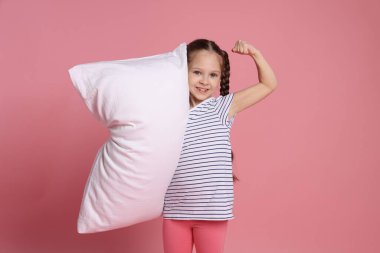 Pembe arka planda yastığı olan tatlı bir kız.