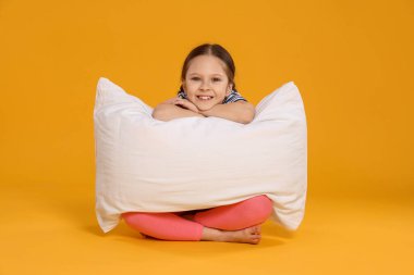 Turuncu arka planda yastığı olan tatlı bir kız.