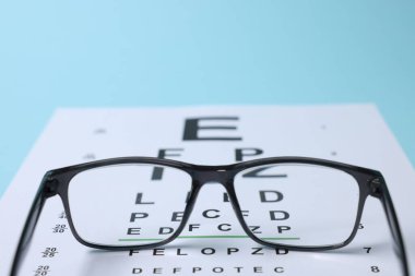 Açık mavi arkaplanda gözlük ve görüş testi grafiği, yakın plan