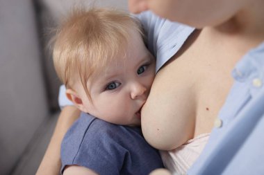 Anne küçük bebeğini evde emziriyor, yakın plan.