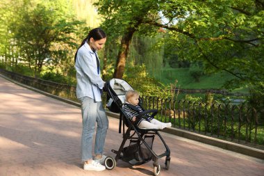 Anne bebeğiyle parkta bebek arabasında yürüyor. Metin için boşluk