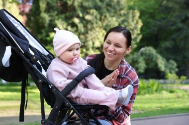 Parkta bebek arabasında sevimli bebeğiyle annesi
