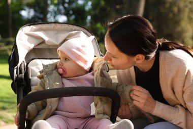 Parkta bebek arabasında sevimli bebeğiyle annesi