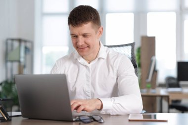 Ofiste masada dizüstü bilgisayarda çalışan adam