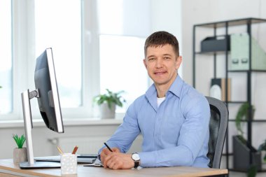 Ofiste masa başında çalışan yakışıklı adam.