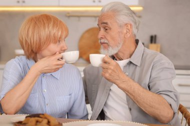 Mutfaktaki ahşap masada birlikte kahvaltı eden sevimli yaşlı çift.