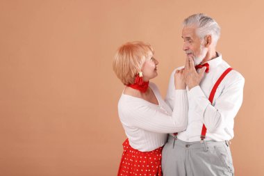 Açık kahverengi arka planda sevimli yaşlı çift, mesaj için yer var.