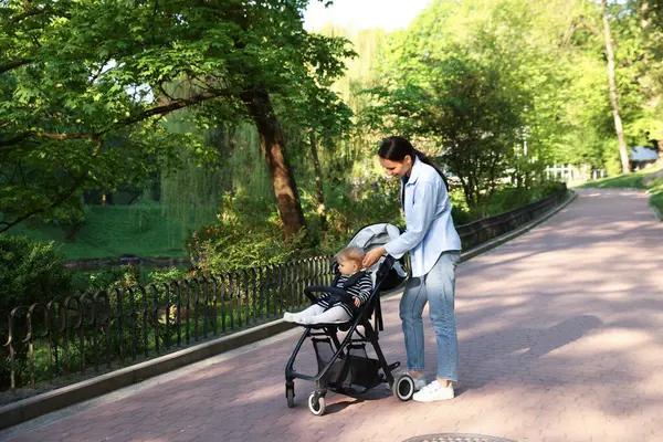Anne bebeğiyle parkta bebek arabasında yürüyor. Metin için boşluk