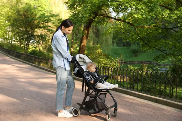 Anne bebeğiyle parkta bebek arabasında yürüyor. Metin için boşluk