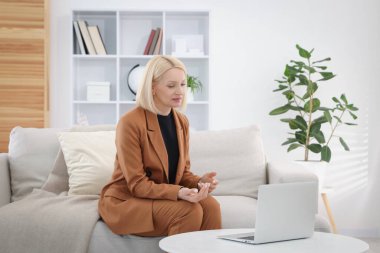 Ofisteki koltukta dizüstü bilgisayarla çalışan profesyonel bir psikolog.