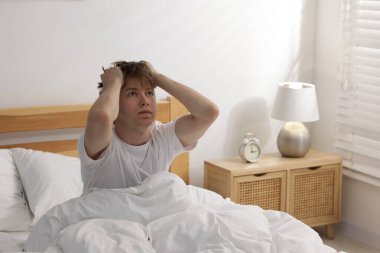 Tired man suffering from insomnia in bed indoors