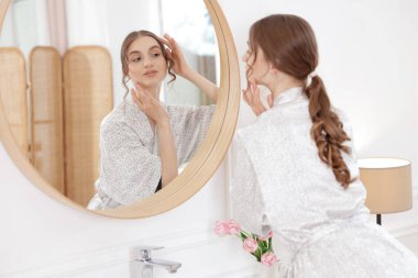 Güzel bir kadın aynada kendine bakıyor.