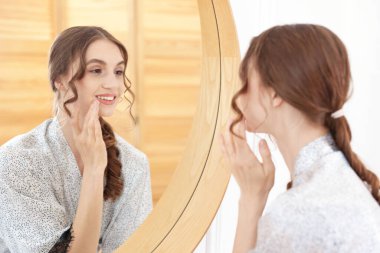 Güzel bir kadın aynada kendine bakıyor.