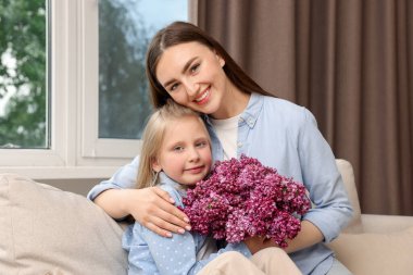 Anne ve kızı evde bir buket leylak çiçekleriyle