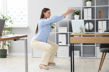 Ofiste masa başında egzersiz yapan güzel bir kadın.