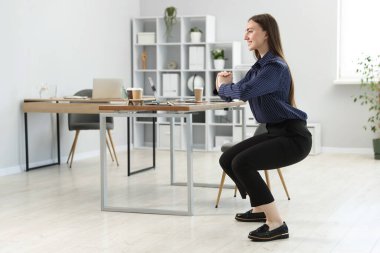 Ofiste masa başında egzersiz yapan güzel bir kadın.