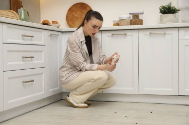Mutfaktaki hamamböceklerine böcek ilacı sıkan bir kadın. Haşere sorunu