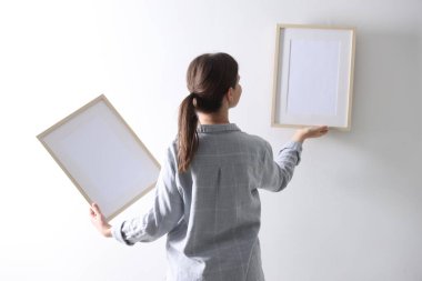Beyaz duvara boş çerçeveler asan kadın, arka plan