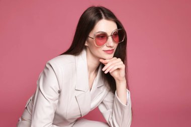 Pembe arka planda şık giyinmiş güzel bir kadının moda portresi.