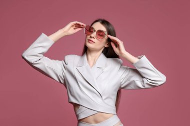 Pembe arka planda şık giyinmiş güzel bir kadının moda portresi.