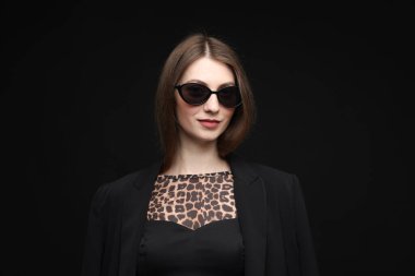 Siyah arka planda şık giyinmiş güzel bir kadının moda portresi.