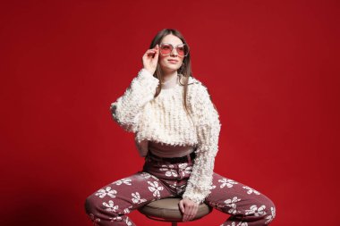 Kırmızı arka planda şık giyinmiş güzel bir kadının moda portresi.