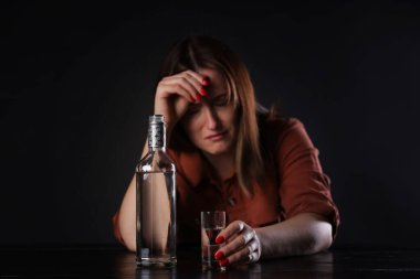Alkol bağımlılığı. Masasında votka olan sefil bir kadın.