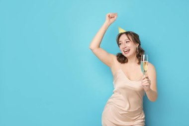 Doğum günü kutlaması. Açık mavi arka planda bir bardak köpüklü şarap içen kadın. Metin için boşluk