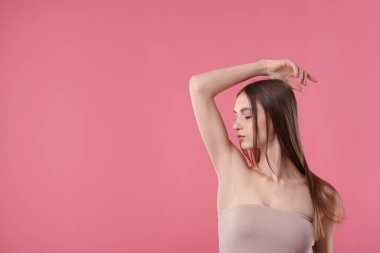 Pembe arkaplandaki epilasyondan sonra pürüzsüz cilt gösteren genç kadın, metin için boşluk