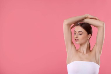 Pembe arkaplandaki epilasyondan sonra pürüzsüz cilt gösteren genç kadın, metin için boşluk