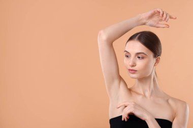 Bej arkaplandaki epilasyondan sonra pürüzsüz cilt gösteren genç kadın, metin için boşluk