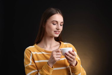 Kahverengi arka planda kahve fincanı olan bir kadın.