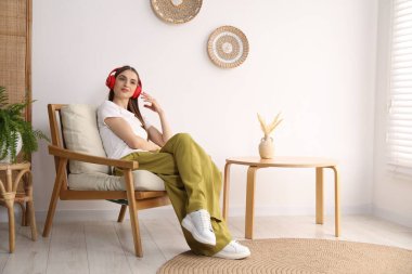 Kulaklıklı güzel bir kadın evdeki rahat koltukta dinleniyor.