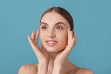 Açık mavi arka planda büyüleyici genç bir kadının portresi.