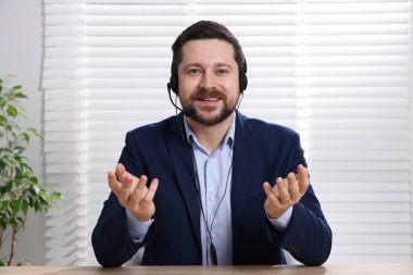 Gülümseyen çevrimiçi hoparlör. İçerideki masada ağlar, web kamerasından görüntü.