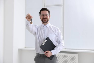 Emlakçının elinde evin anahtarı, anahtarlık ve pano var.