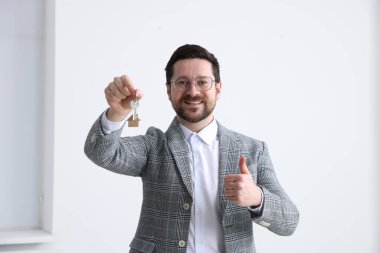 Emlakçının elinde anahtarlık, ev şeklindeki anahtarlık var.