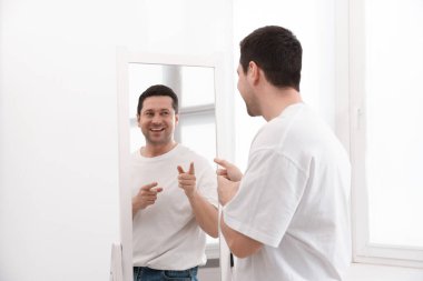 Yakışıklı adam aynada kendine bakıyor.