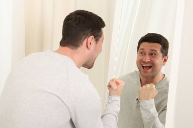 Yakışıklı adam aynada kendine bakıyor.