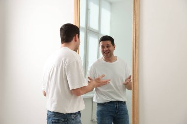 Yakışıklı adam aynada kendine bakıyor.